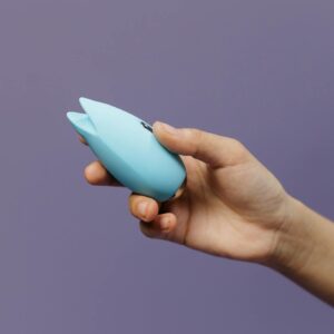 A blue silicone sex toy held in hand against a solid purple background, promoting self-love and sexuality.