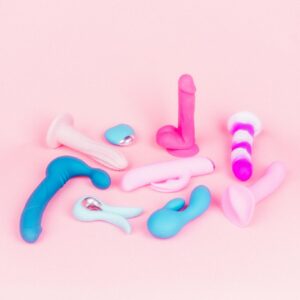 A variety of vibrators and sex toys in bright colors on a pink backdrop.