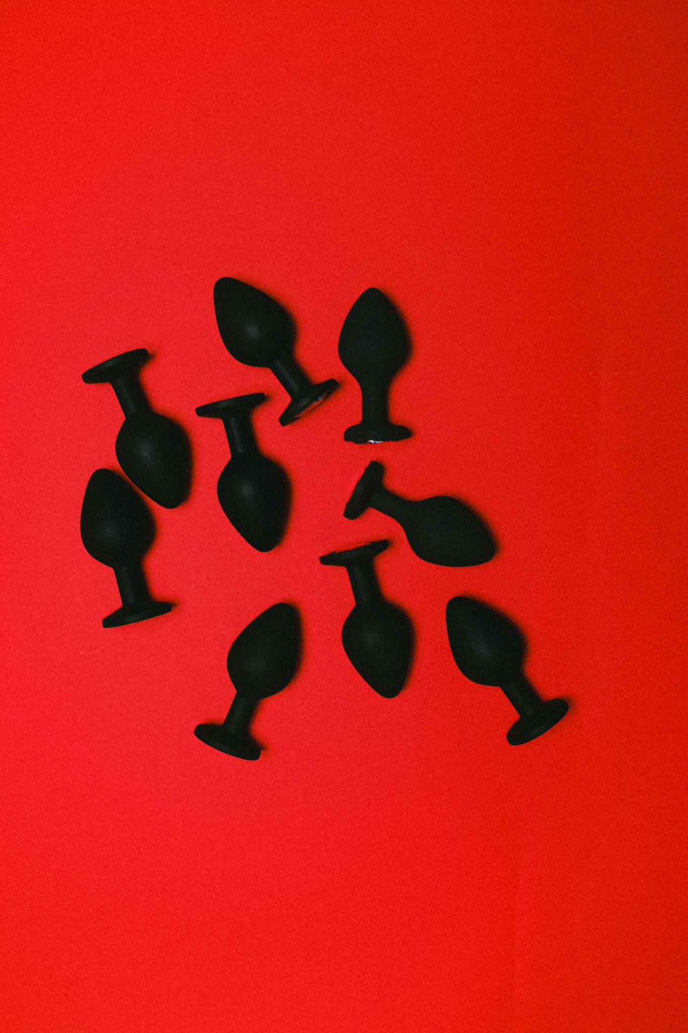 Black silicone sex toys displayed on a bold red background, enhancing sensuality and luxury.