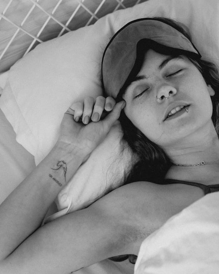 A serene black and white portrait capturing a woman sleeping with eyes closed and a sleep mask.