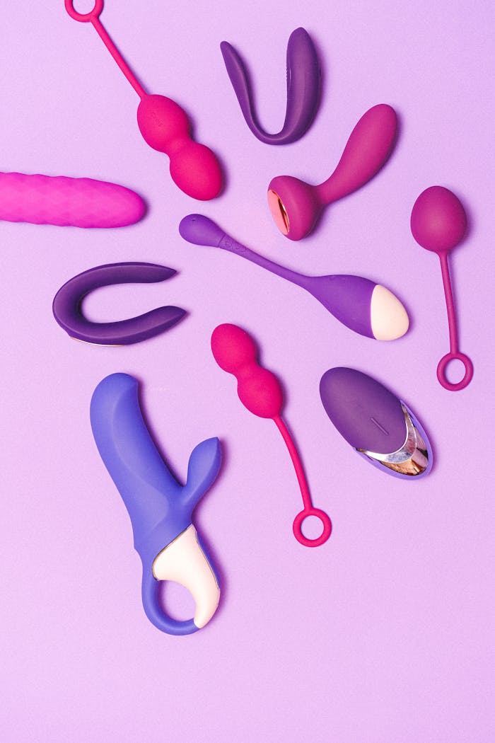 Colorful sex toys beautifully arranged on a purple surface, showcasing variety and vibrancy.