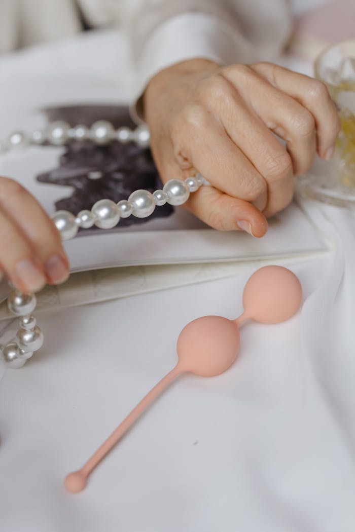 Close-up of hands with pearls and kegel balls, symbolizing elegance and women's health.