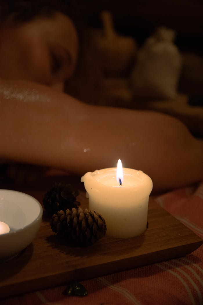A serene spa scene with a lit candle on a wooden board, suggesting relaxation and tranquility.