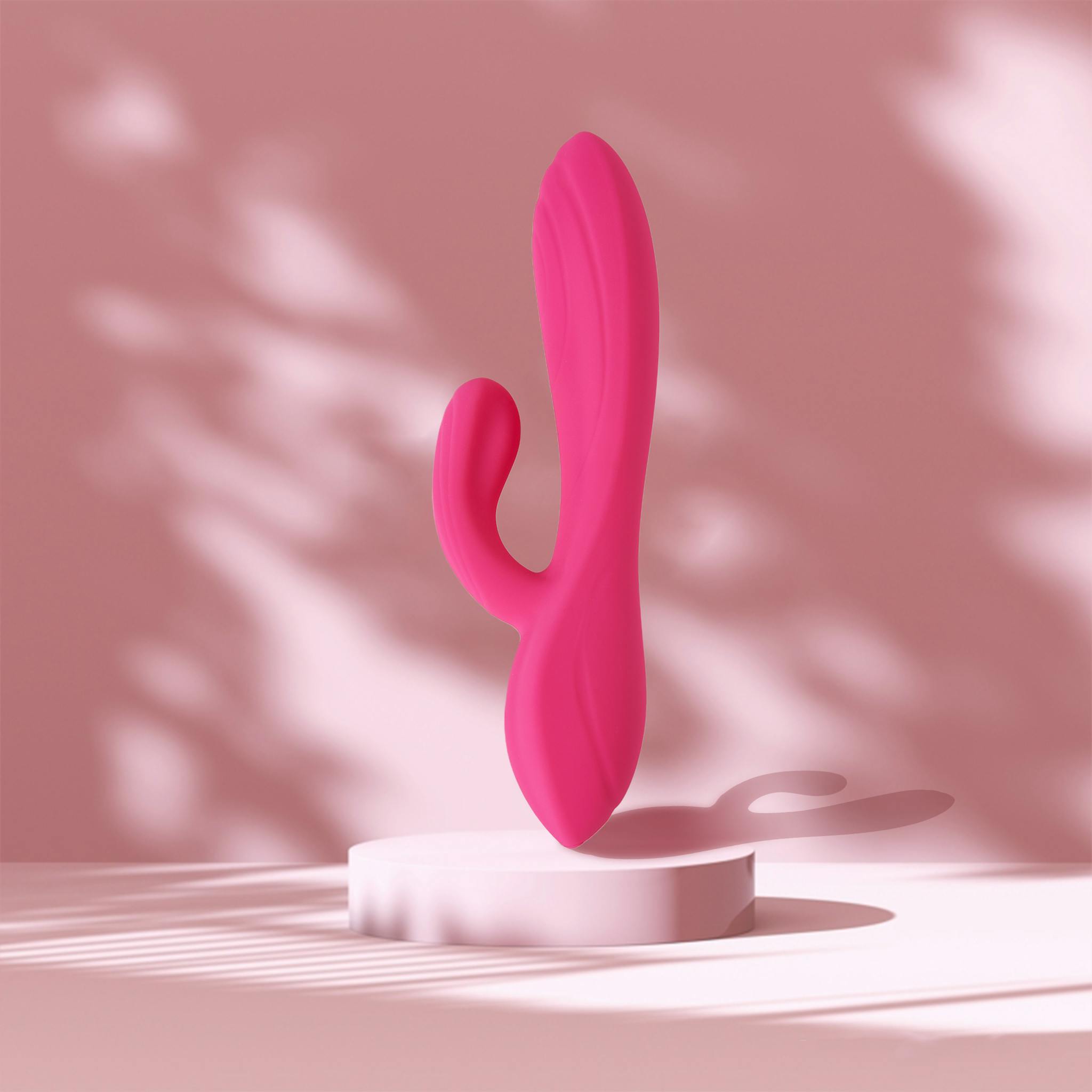 Stylish pink rabbit vibrator displayed on a platform against a soft background for product photography.