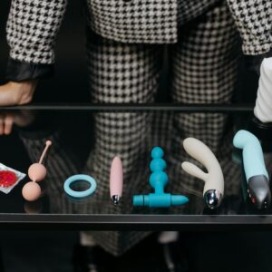 Various sex toys and condoms displayed on a glass table promoting safe sex and self love.