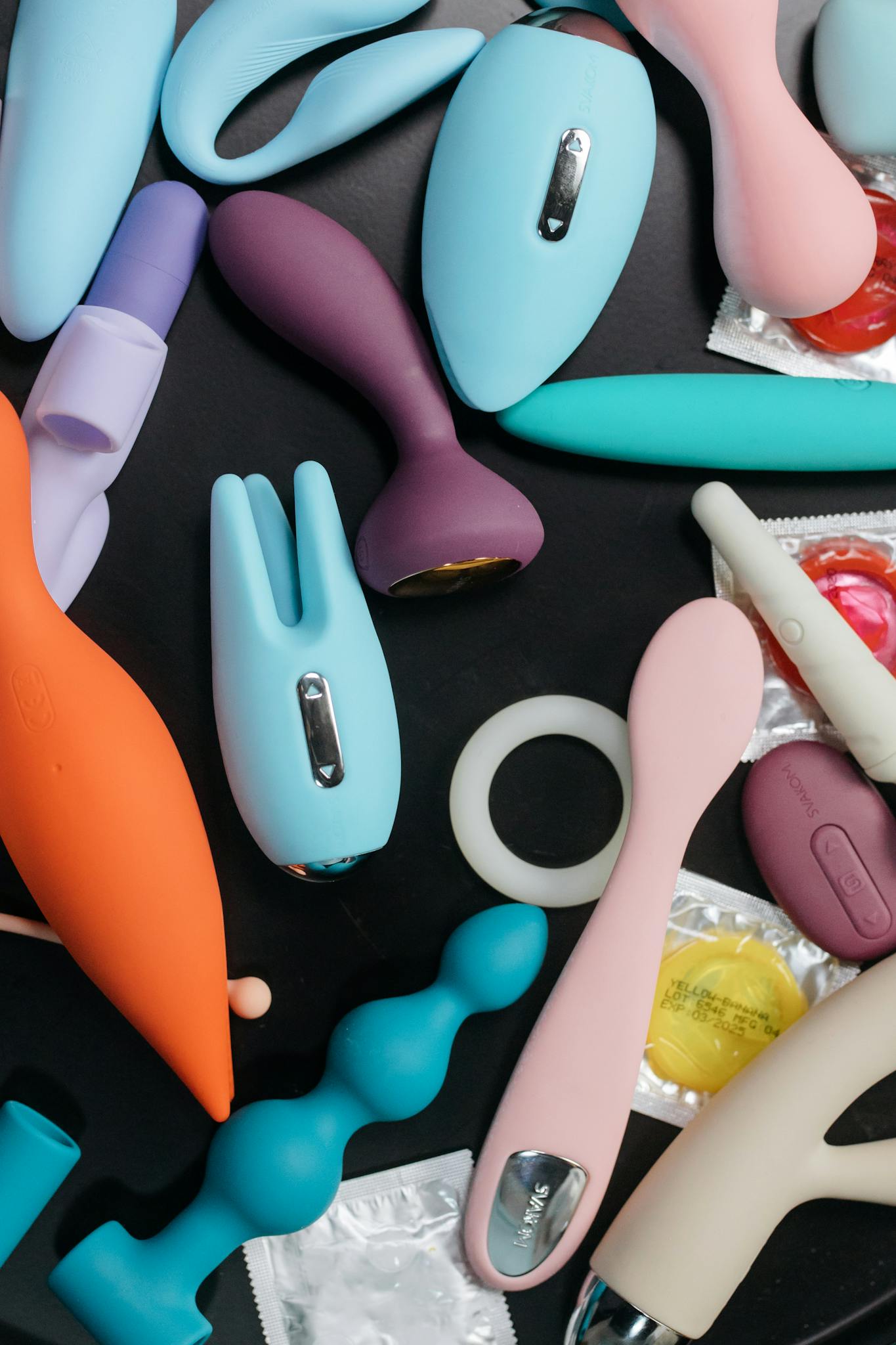 Vibrant flat lay of diverse adult toys and accessories on a black background.